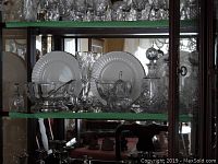 Hutch shelf view showing assortment of decanters, champagne flutes, bowls, creamer and sugar bowl