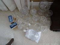 Overview of crystal glassware assortment including vases, salt and pepper, creamer and sugar, bowls, candy dishes and more on carpet.