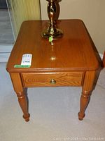 Solid wood end table top surface with auction sticker and brass lamp