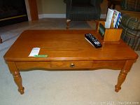 Front view of solid oak coffee table showing turned legs and single drawer with brass knob