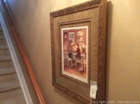Framed art print hanging on a wall beside staircase