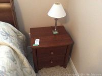 Full view of wooden nightstand with lamp on top
