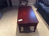 Full front view of the polished wood coffee table placed on carpeted floor between furniture.