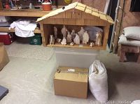 Front view of wooden stable with mother of pearl nativity figures arranged inside.