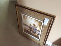 Angled full view of framed print leaning against wall on carpet