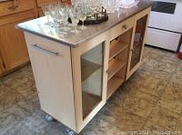 Front three-quarter view showing stainless steel top with glassware and light wood base