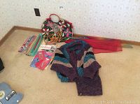 Full lot display including books, knitting needles, crochet hooks, fabric handbag, striped knitted sweater, and sheer fabric.