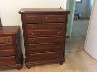 Front view of the tall boy dresser showing 5 drawers with round wooden knobs and some wear on the wood surface