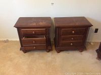 Front view of pair of wooden night stands with three drawers each.
