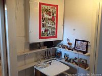 Photo shows a corner shelf with assorted collectible spoons, decor items including a deer figurine, small frames, chess set, and a white drop leaf table below the shelf.