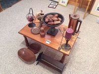 Photo showing small wooden table with all items arranged on and around it, including wooden bowls, metal percolator, candle holder with purple candle, pedestal bowl with wooden pieces, and elephant figurine.