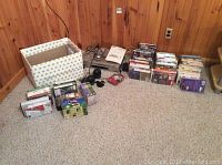 Photo showing silver Samsung SV-5000W VCR player, remote control, wired headphones, and large collection of VHS tapes grouped on carpeted floor.