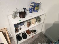 Overall view of the white book shelf with various items displayed on three shelves.