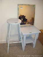 Photo of wooden stool, square wooden table, and rectangular mirror leaning against the wall.