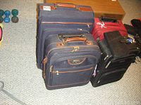 Overview of 4 luggage pieces including navy blue, black, and red suitcases shown on carpet floor.