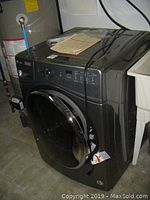Side view of Whirlpool front load washer connected to water supply and drain