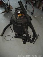 Full view of black Craftsman 45L shop vacuum with connected hose and floor nozzle attachment resting on concrete floor.