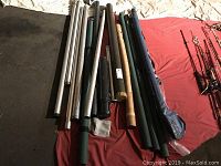 Photo of laid out fishing rod holders of metal and plastic, some cylindrical tubes, on fabric surface.