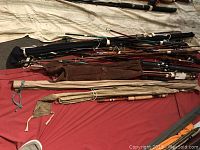 Overview of multiple fishing rods with covers and different grips, laid out on a red surface