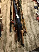 Overview of eleven assorted rods laid out on bedding, showing variety of materials and handles
