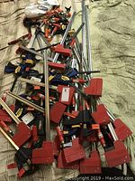 Overall view of metal bar clamps with red and black E-Z Hold II jaws and Irwin Quick-Grip clamps