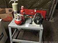 Photo showing the entire lot including the fire extinguishers, grinder motor on metal table, and red tool box with tools.