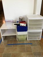 Wide shot of the lot showing two stackable drawer units, a white open shelf, various plastic shoeboxes stacked inside each other, and lint brushes on top