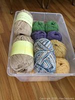 Bin of 14 skeins of cotton yarn, 4 ply, worsted weight in various colors including yellow, tan, purple, green, and variegated.