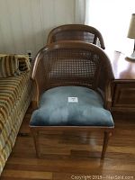 Two caned backed velour accent chairs with solid wood frame. Chairs have curved caned backs and light velour cushion seats. One chair has a broken caned area.