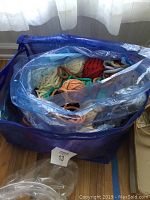 Top view of a blue bag filled with multiple rolled knitted cords in various earth tone and bright colors, showing the quantity and variety.