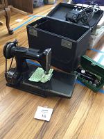 Singer Featherweight sewing machine on base next to open black carrying case and green attachment box