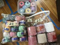Multiple balls of cotton crochet thread size 20 in plastic container showing variety of colors including pastel and bright shades