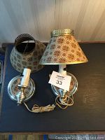Pair of 1950s wall lamps shown on a wooden surface with patterned fabric shades removed from the bases.