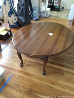 Full view of oval drop leaf wooden coffee table with turned Queen Anne legs and ball feet.