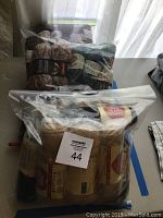 Three plastic bags filled with new and near-new skeins of sport weight yarn in various colors and brands shown on a table.