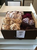 Box filled with multiple skeins of slubby acrylic yarn in various colors and textures.