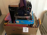 Photo of various office supplies in a box including 3-tab side folders, hanging file folders, pencil holders, notebooks, and organizers.
