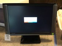 Front view showing the monitor powered on with a display in the center and a green power light on.