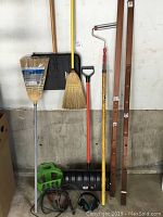 Full lot view showing brooms, shovels, jumper cables, paint roller, ear protectors, hose holder, and trellis