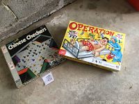 Photo showing boxed Chinese Checkers and Operation games on the floor.