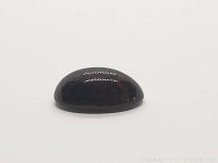 Side view of the oval black opal cabochon showing dome and thickness.