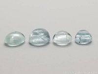 Four oval cabochon blue aquamarine stones arranged in size order from left to right, showing shape and dome profile.