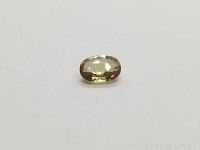 Top and side views of an oval light yellow sapphire on a white background.