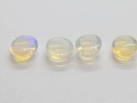 Four loose crystal opals, showing side profile and color flash under direct light.