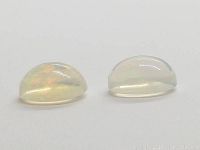Two oval Ethiopian opal cabochons showing dome shape and typical chatoyancy with a milky white base and subtle flashes of color.