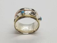 Side angle of the 925 sterling silver spinner ring showing hammered texture, blue turquoise stones, and mixed metal bands in silver, gold, and rose tones.