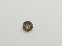 Top view of round cut green yellow Tourmaline gemstone on a white background.