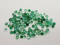 Spread of multiple small round green gemstones on white background