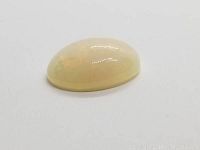 Oval white opal gemstone on a white background showing surface and color properties