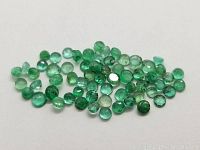 Several round cut emerald gemstones grouped on white background showing various shades of green and translucency.